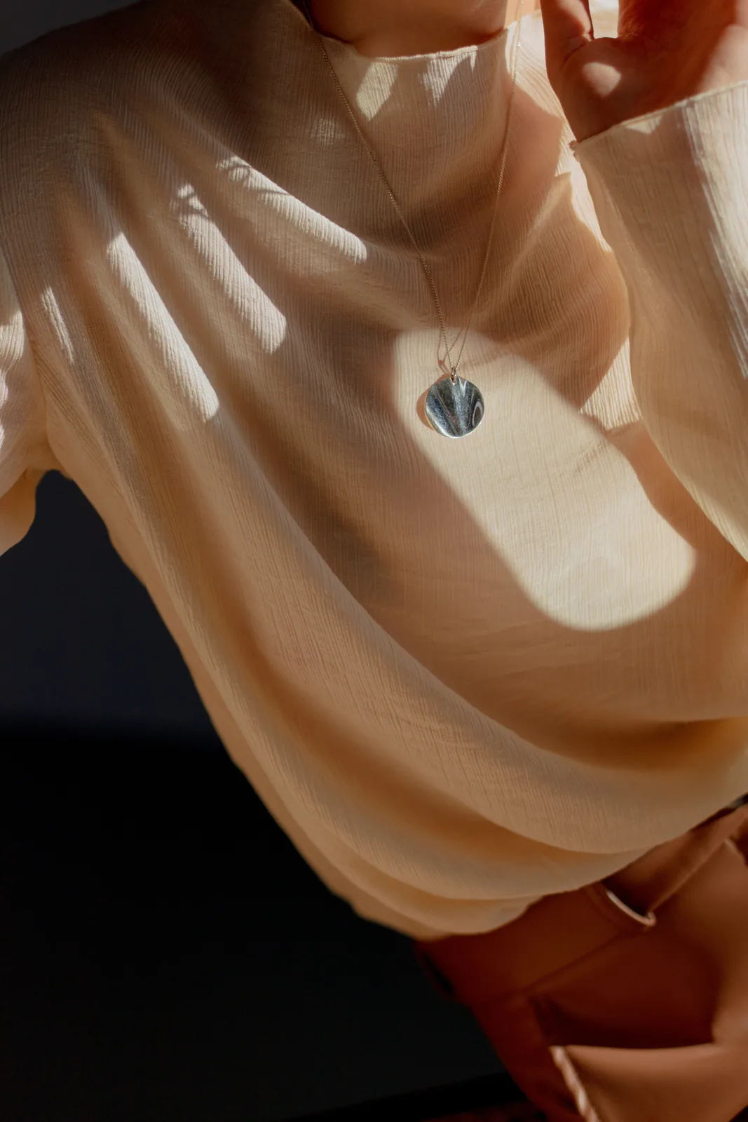 Woman wearing a sculptural pendant in warm natural light